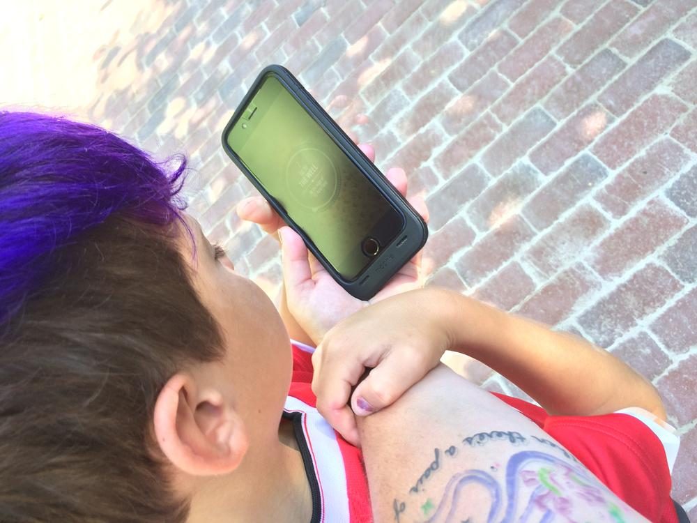 A child fully absorbed in the Agent 711 app, walking along a brick path at Mount Vernon