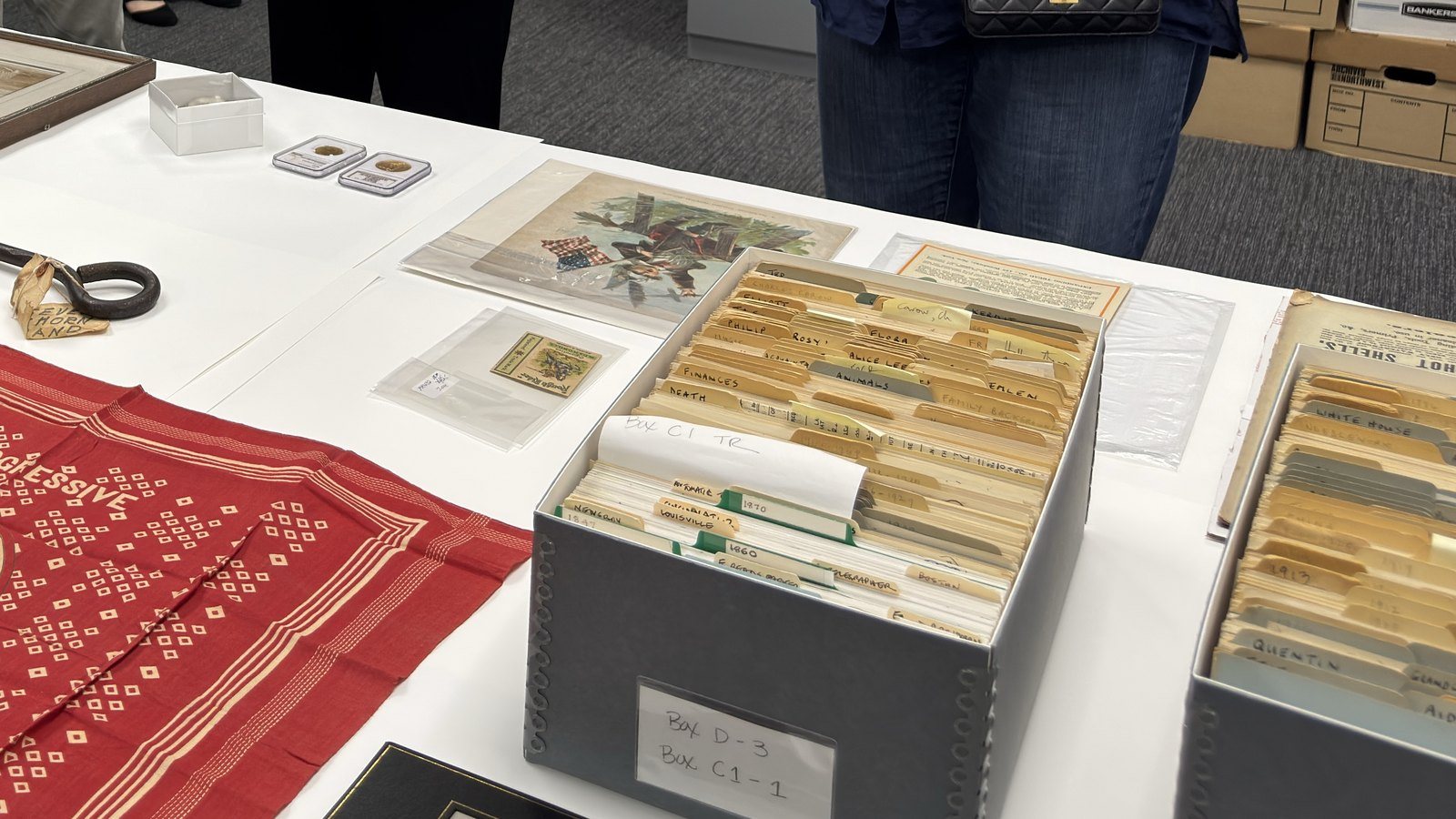 Archival file boxes in the Library's collections workroom, their hand-labelled tab dividers reading Ted, Eleanor, Alice Lee, Quentin, Finances, Animals, White House, alongside sleeved ephemera on a table