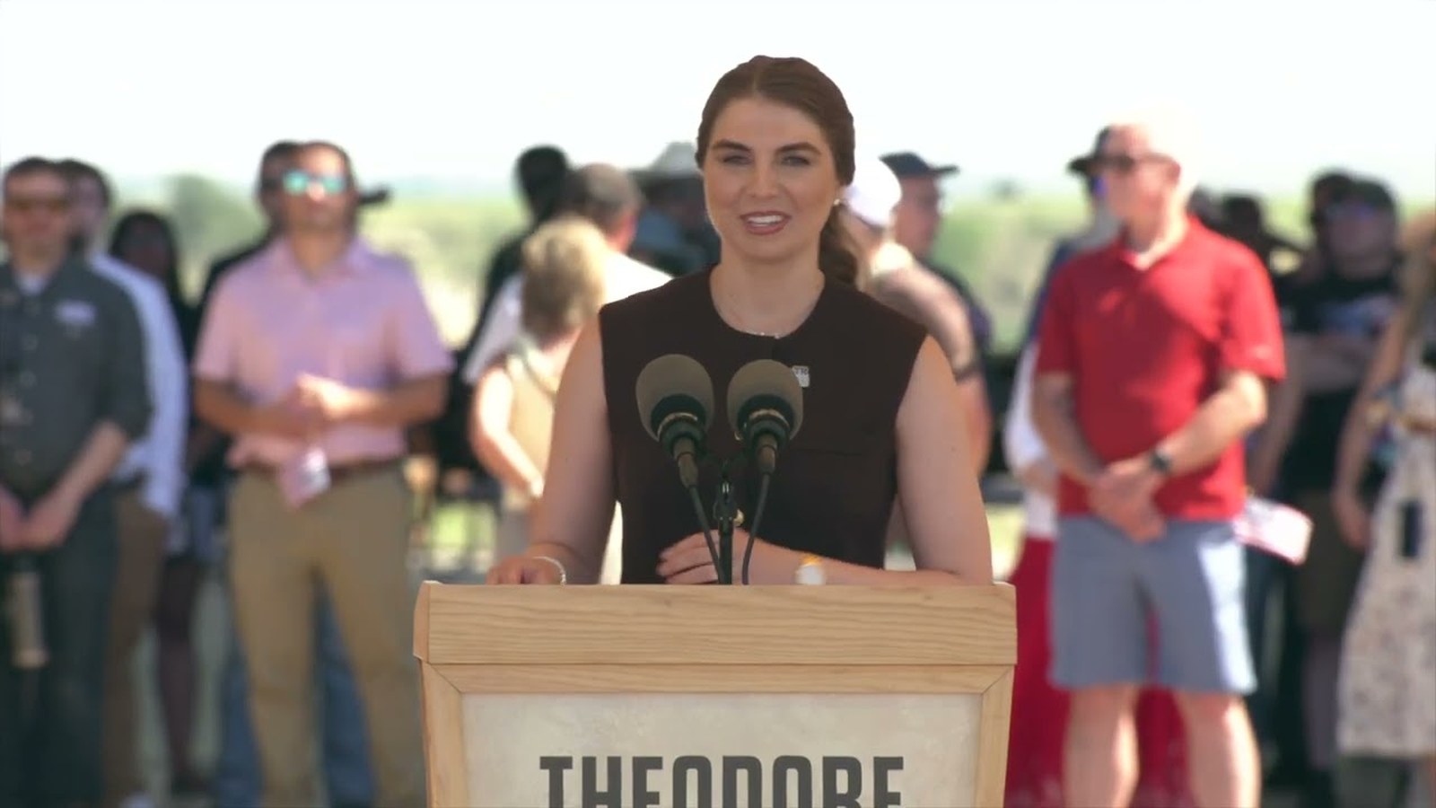 A speaker at the Grand Opening Ceremony podium with the crowd behind