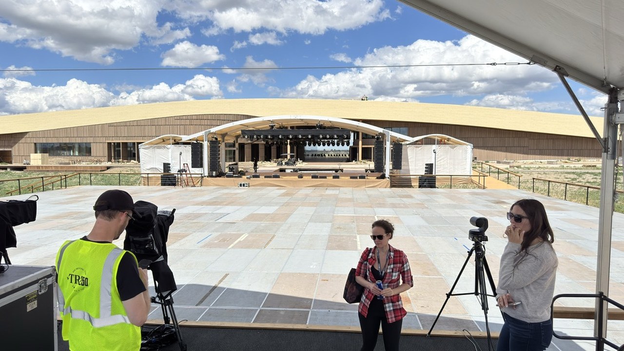 The ceremony stage and lighting rig under construction on the empty plaza, with a media riser tent in the foreground and the Library behind