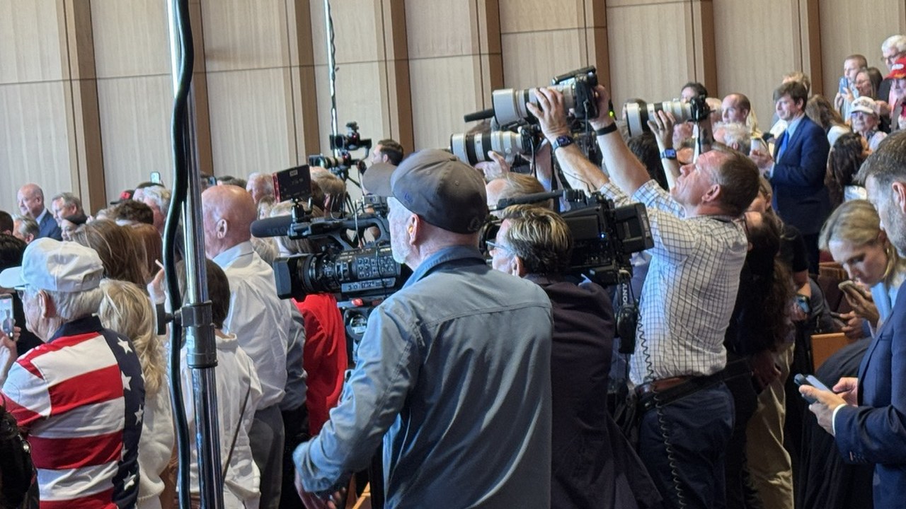 The press riser during the dedication — long lenses, broadcast cameras and photographers packed shoulder to shoulder above the crowd